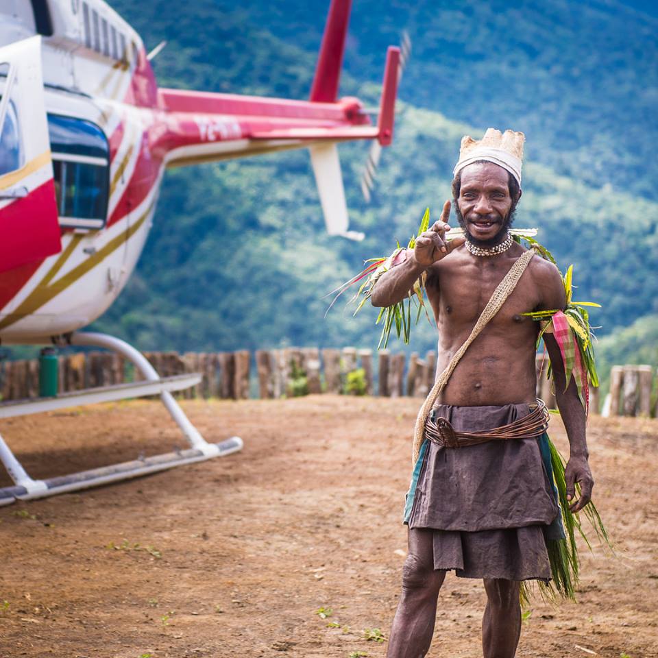 man from Papua New Guinea in traditional garb posing for a picture at a mountain helipad