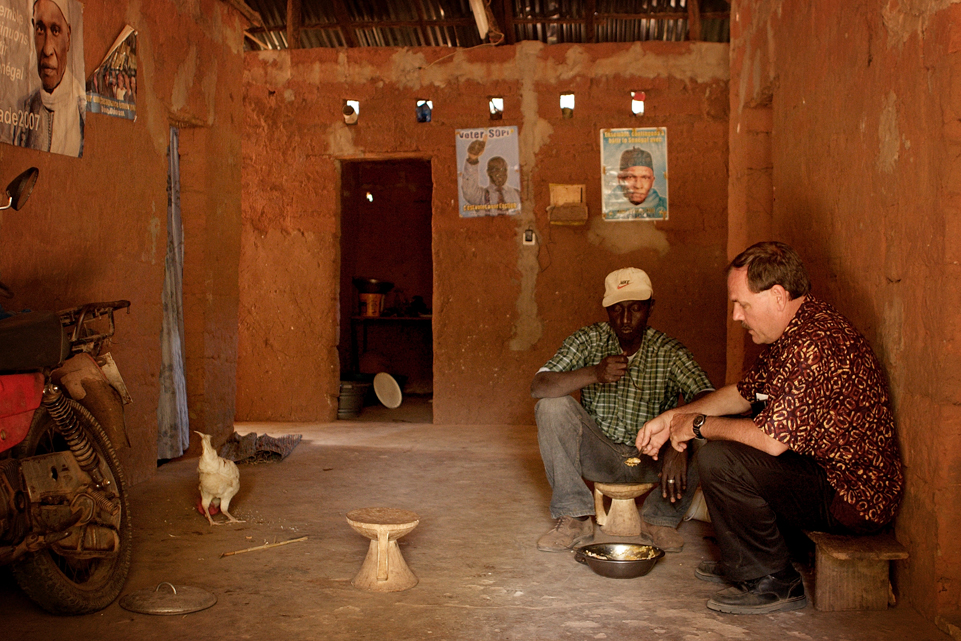 missionary and African friend sitting and making tea