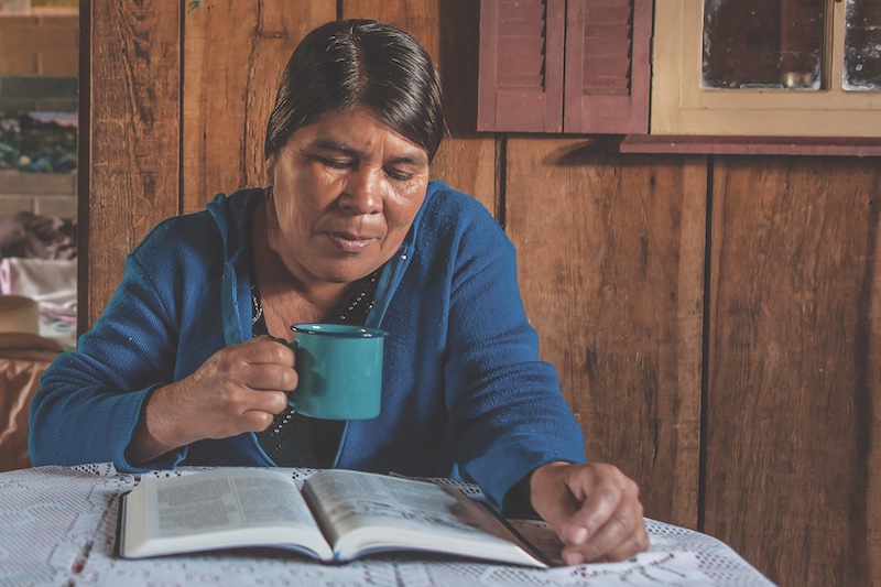 woman reading while holding mug